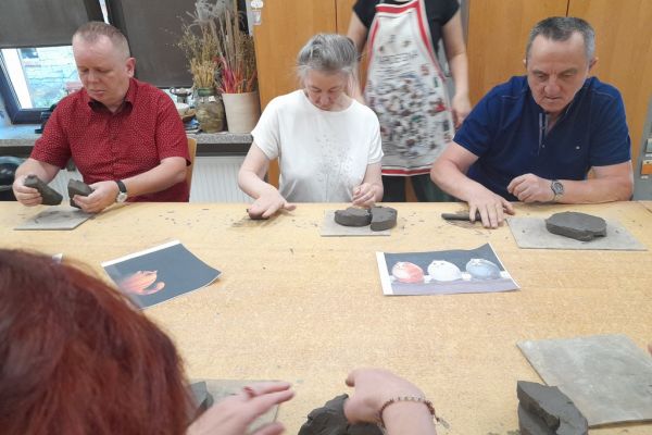 Mieszkańcy w pracowni lepią z gliny.
