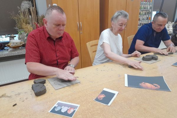 Mieszkańcy w pracowni lepią z gliny.
