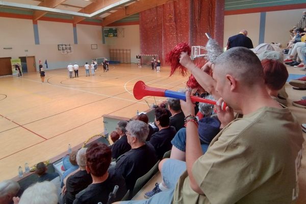Mieszkańcy w hali sportowej siedza i kibicują drużynie UTW z Gminy Redzikowo podczas spartakiady.