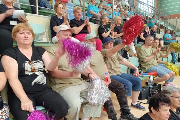Mieszkańcy w hali sportowej siedza i kibicują drużynie UTW z Gminy Redzikowo podczas spartakiady.