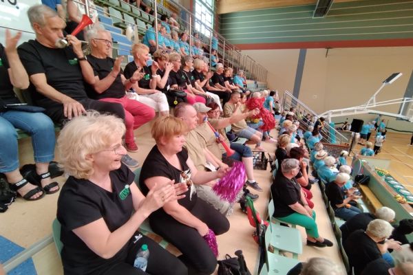 Mieszkańcy w hali sportowej siedza i kibicują drużynie UTW z Gminy Redzikowo podczas spartakiady.
