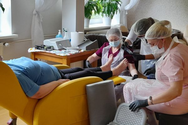 Panie podolog wykonują zabieg na stopach mieszkanki.