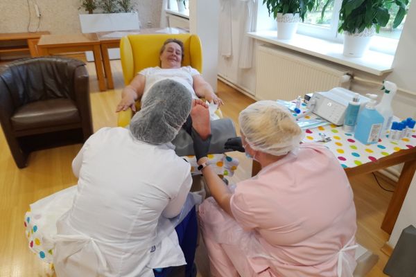 Panie podolog wykonują zabieg na stopach mieszkanki.