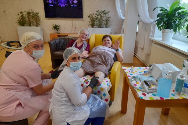 Panie podolog wykonują zabieg na stopach mieszkanki.