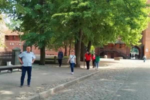 Grupka mieszkańców spaceruje alejami miasta Tczewa.