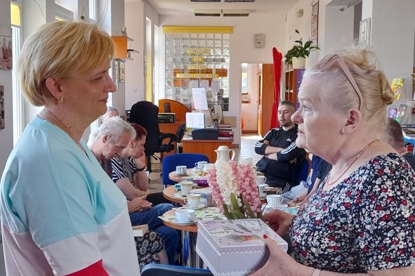 Mieszkanka wręcza bibliotekarce herbaciarkę i kwiatki.