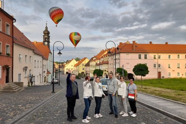 Mieszkańcy machają do lecących balonów.