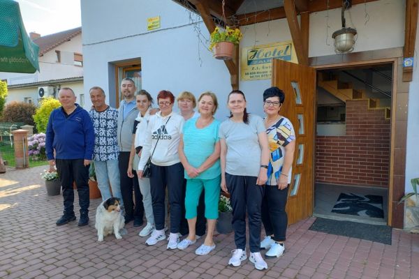 Zbiorowe zdjęcie mieszkańców przed hotelem wraz z właścicielami.