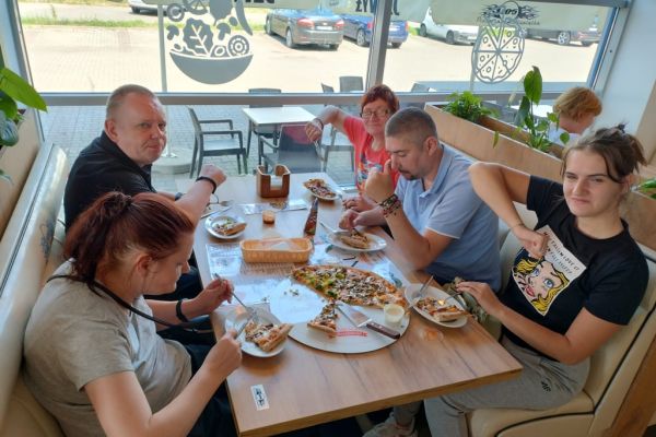 Mieszkańcy jedzą pizzę.