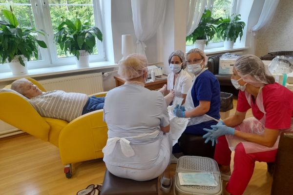 Panie podolog wykonują zabiegi na stopach mieszkanki.