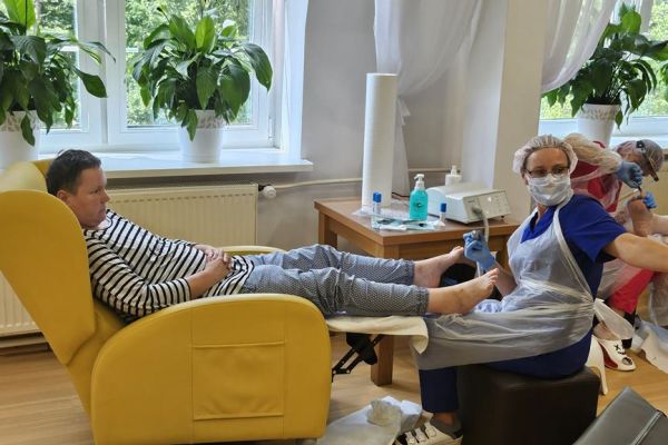 Panie podolog wykonują zabiegi na stopach mieszkanki.