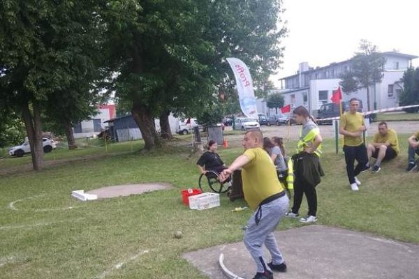 Mieszkaniec rzuca na zawodach sportowych , wokoło inni uczestnicy.