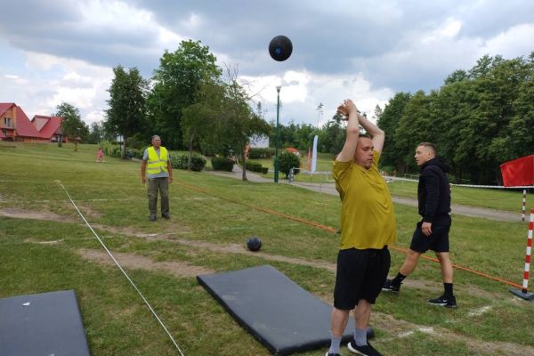Mieszkaniec rzuca na zawodach sportowych , wokoło inni uczestnicy.