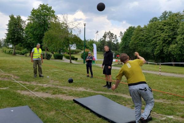 Mieszkaniec rzuca na zawodach sportowych , wokoło inni uczestnicy.