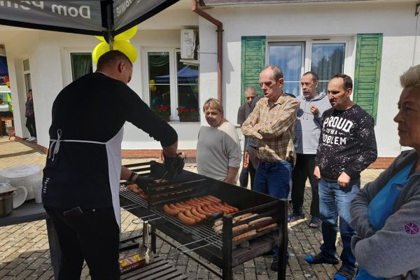 Uczestnicy pikniku przy grillu.