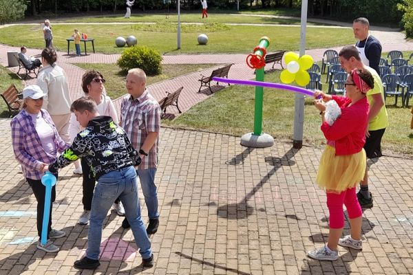 Uczestnicy pikniku łapia bańki a animatorka kręci balony.