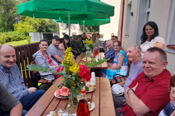 Uczestnicy pikniku siedzą przy poczęstunku.