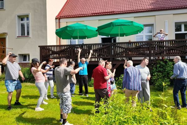 Uczestnicy pikniku tańcza na trawie.