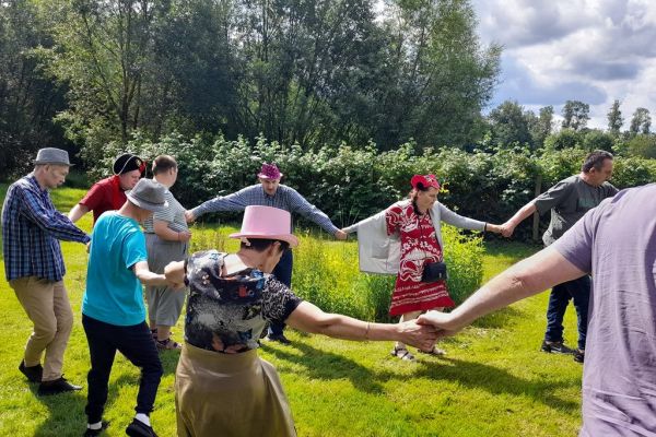 Uczestnicy pikniku tańcza na trawie.