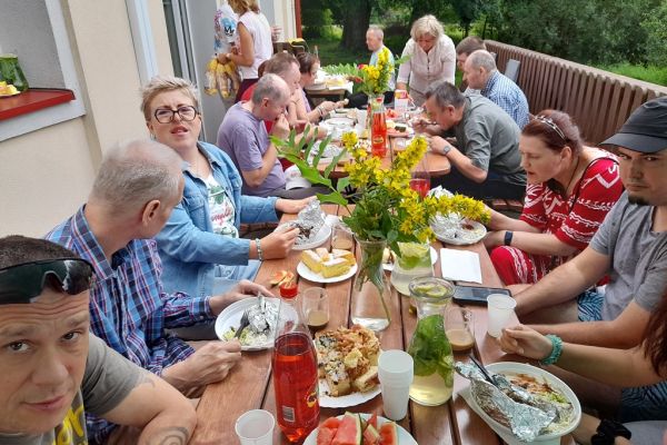 Uczestnicy pikniku siedzą przy poczęstunku.