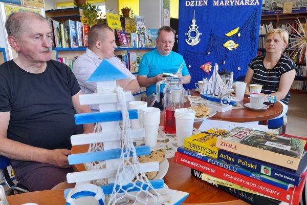 Mieszkańcy siedzą przy stolikach w bibliotece.