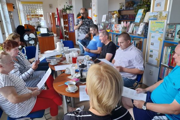 Mieszkańcy siedzą przy stolikach w bibliotece.