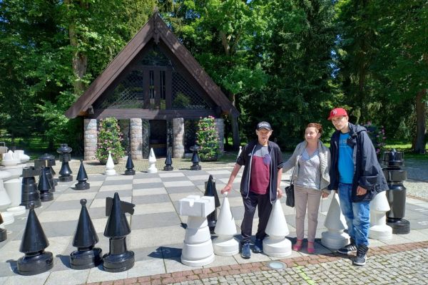 Dwoje mieszkańców i Pani Kierownik przy dużuch plenerowych szachach..