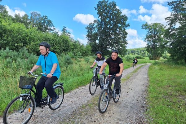 Mieszkańcy jada na rowerach drogą polną.