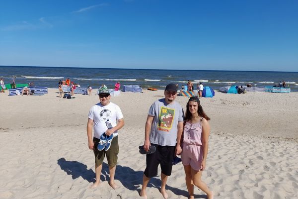 Troje mieszkańców stoi na plaży.