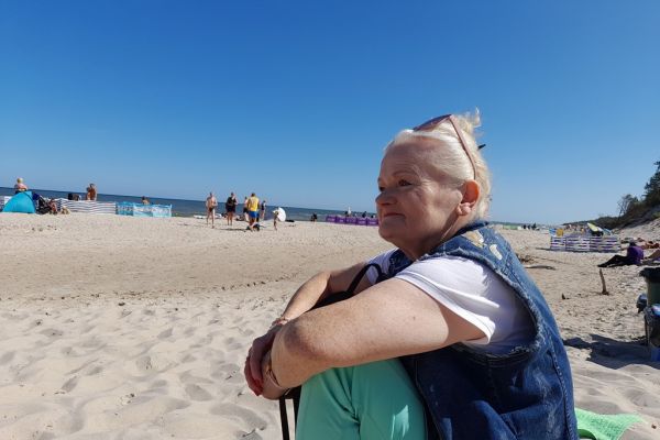 Mieszkanka siedzi na plaży.