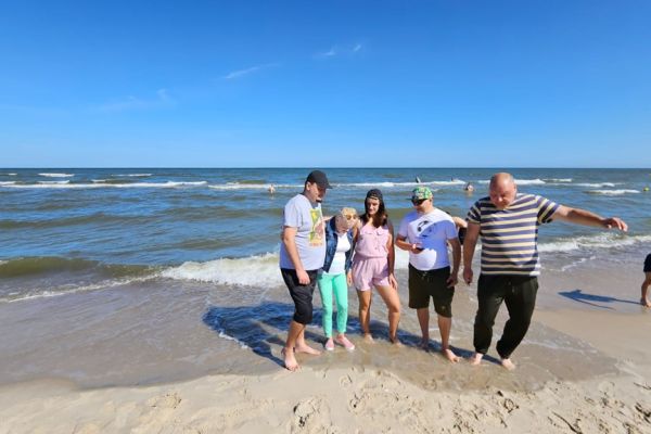 Pięcioro mieszkańców stoi na plaży.