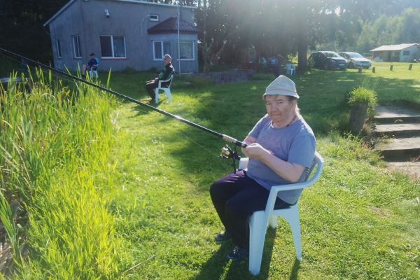 Mieszkaniec siedzi i łowi ryby.