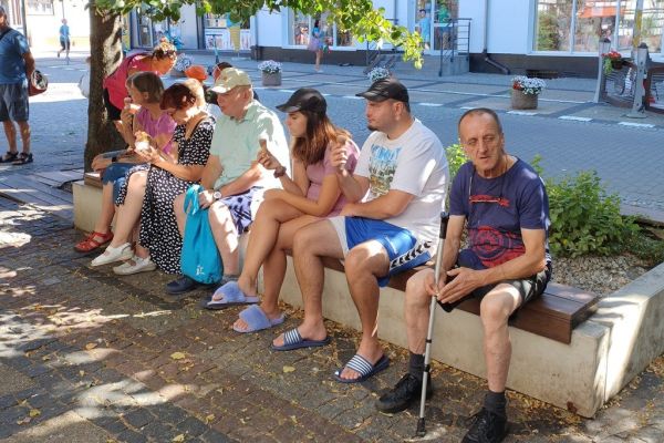 Mieszkańcy siedza na ławeczkach.