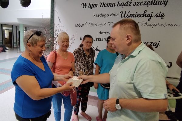 Nasi mieszkańcy przekazuja kopertę mieszkance wioski.