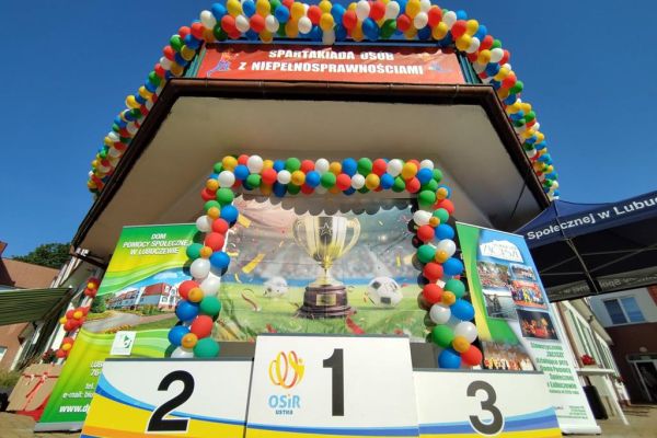 Baner z pucharem, baner z nazwą imprezy, podium, a wszystko udekorowane balonami.