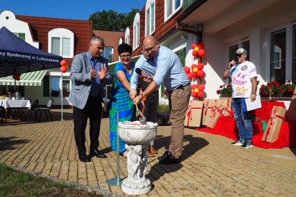 Odpalanie znicza przez władze powiatu i dyrektorkę domu.
