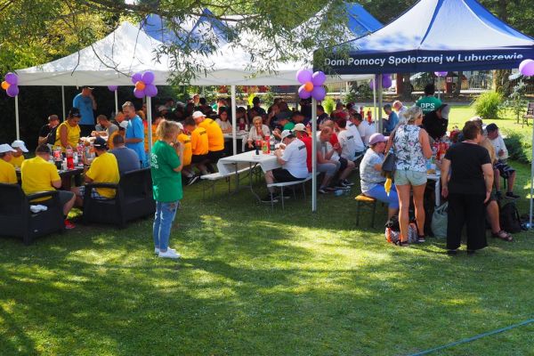 Uczestniczące drużyny siedzace przy stolikach pod namiotami.