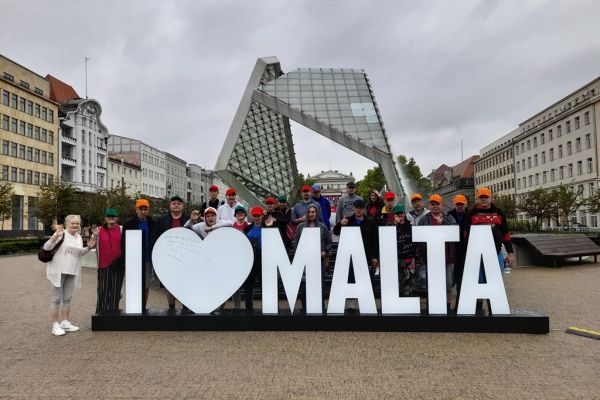 Wycieczkowa grupa na zdjęciu przy dużej fontannie w Poznaniu.