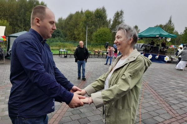 Mieszkanka tańczy z innym uczestnikiem festynu.