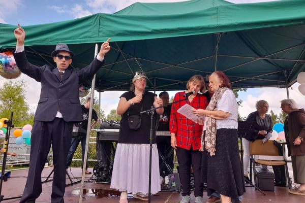 Nasza mieszkanka i troje innych uczestników festynu śpiewa na scenie.