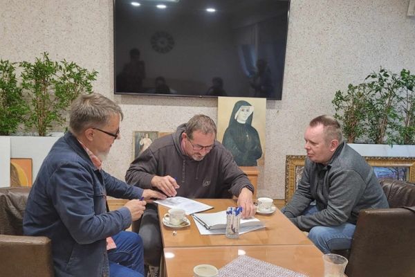 Mieszkaniec siedzi w kawiarence z przedstawicielami muzeum.