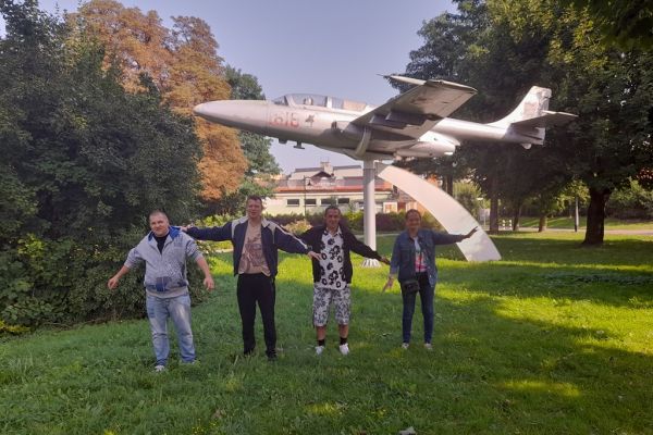 Mieszkańcy stoja pod pomnikiem samolotu.