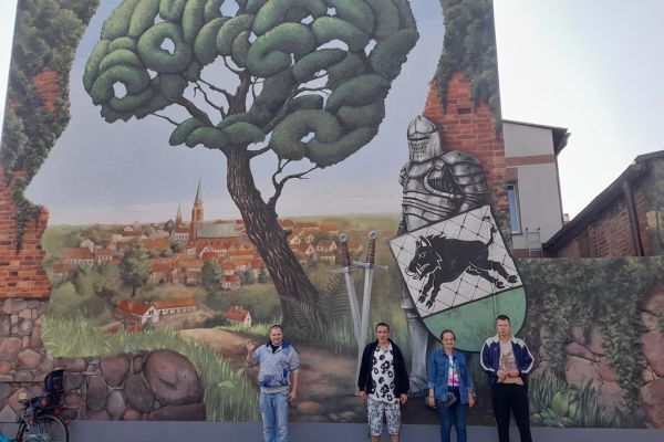 Mieszkańcy stoją pod muralem.