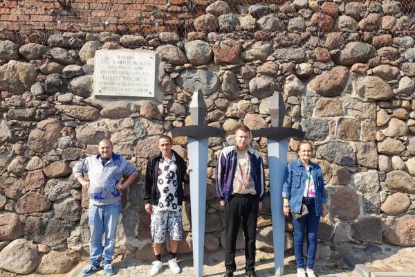 Mieszkańcy stoją przy pomniku dwóch mieczy.