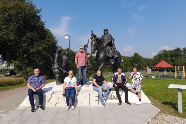 Mieszkańcy siedza przy pomniku.