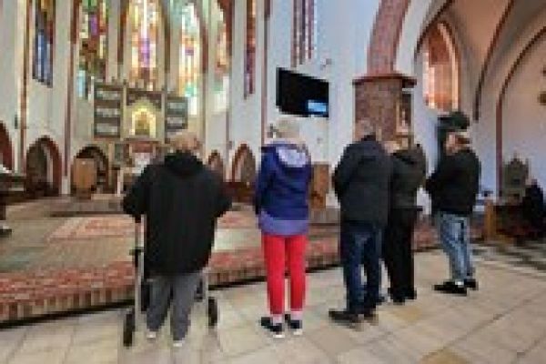 Pięcioro mieszkańców stoi przed ołtarzem w kościele.