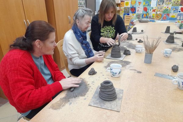 Mieszkańcy na warsztatach ceramicznych rzeźbią w glinie.