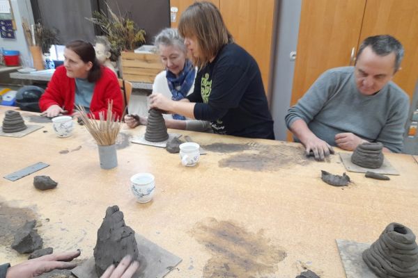 Mieszkańcy na warsztatach ceramicznych rzeźbią w glinie.