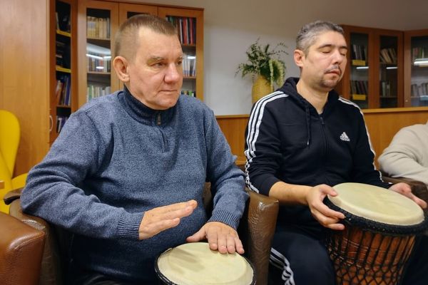 Mieszkańcy uderzają w bębny siedząc.