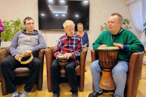 Mieszkańcy uderzają w bębny siedząc.